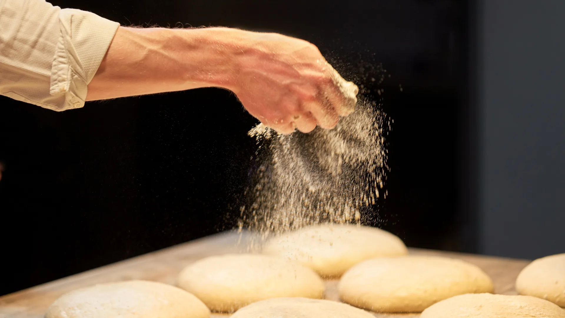 Boulanger qui farine des pâtons sur tôle dans l'atelier de la Maison Lefèvre